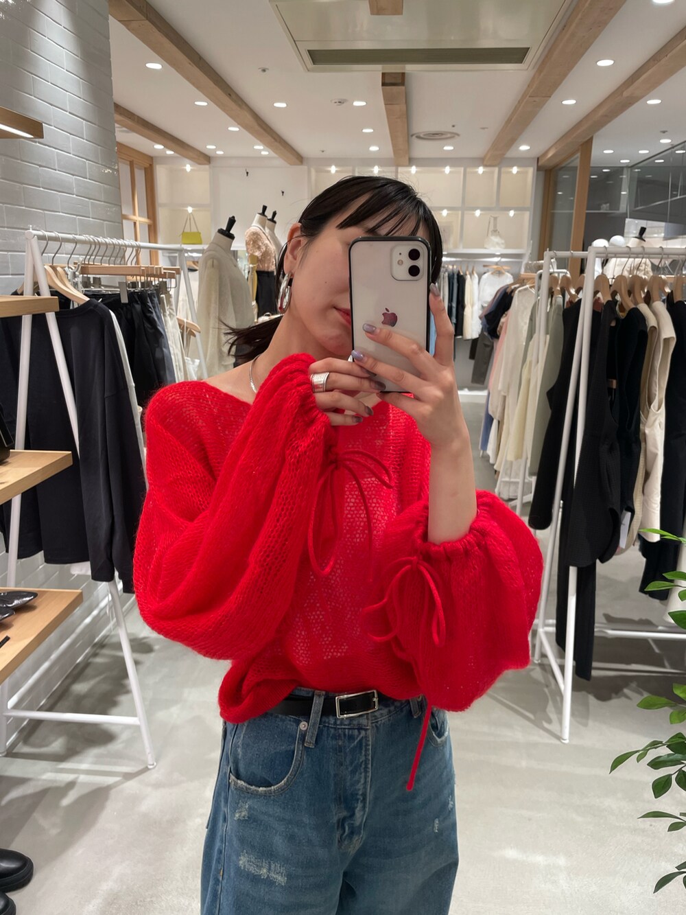 レッド系のニット/セーター、ブルー系のデニムパンツを着用したレディースの秋コーディネートの4枚目の写真