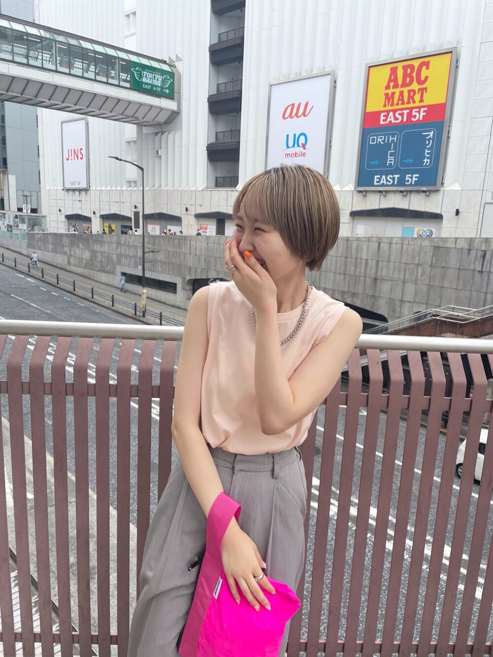 ブルー系のハンドバッグ、グレー系のスラックスを着用したレディースの夏コーディネートの2枚目の写真