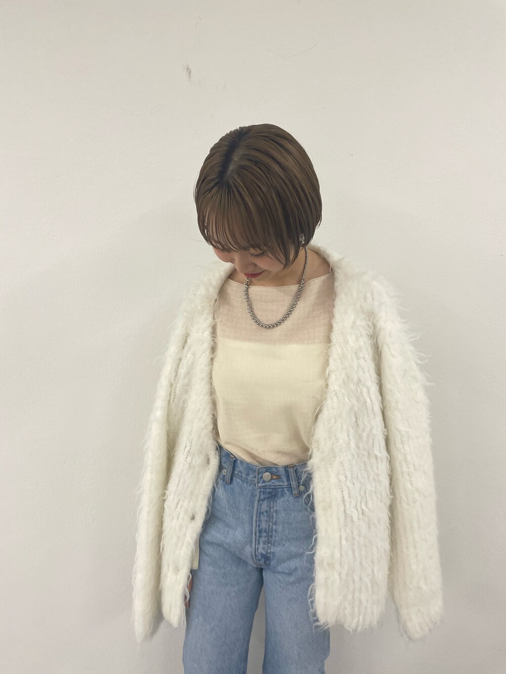 ホワイト系のカーディガン/ボレロ、ベージュ系のニット/セーター、ブルー系のデニムパンツを着用したレディースの秋コーディネートの3枚目の写真