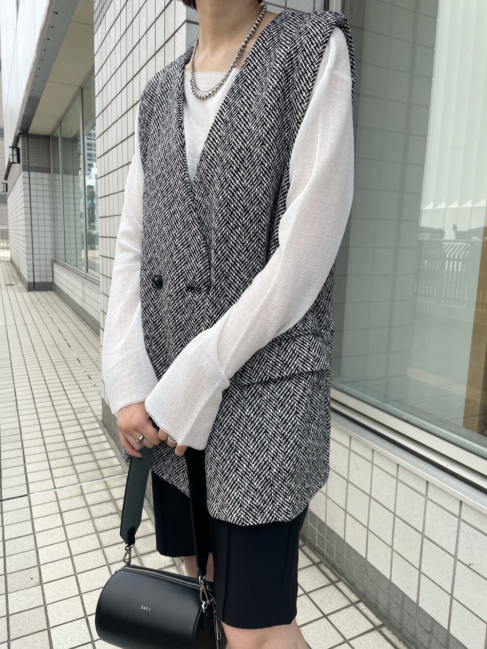 ブラック系のベスト、ホワイト系のニット/セーター、ブラック系のその他パンツを着用したレディースの秋コーディネートの3枚目の写真