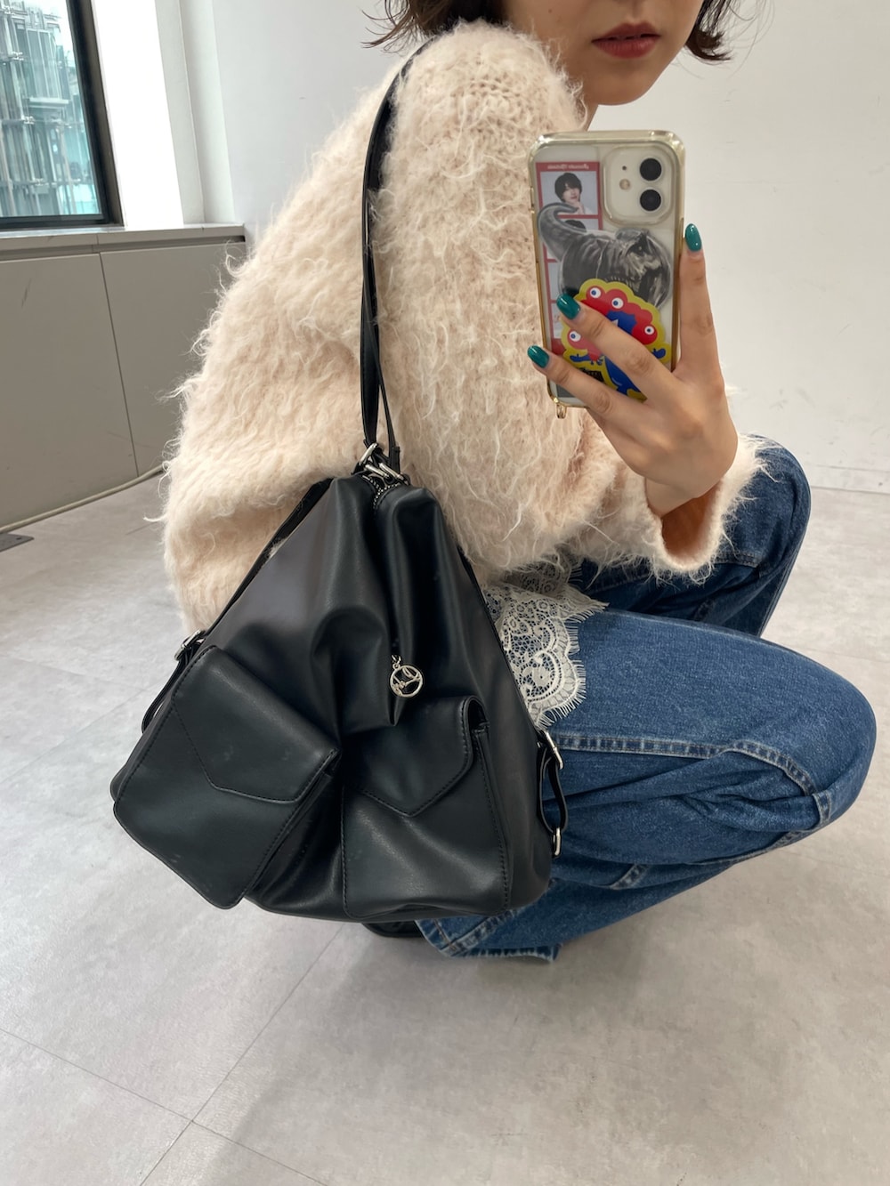 ピンク系のニット/セーター、ブラック系のトートバッグ、ブルー系のデニムパンツを着用したレディースの秋コーディネートの2枚目の写真