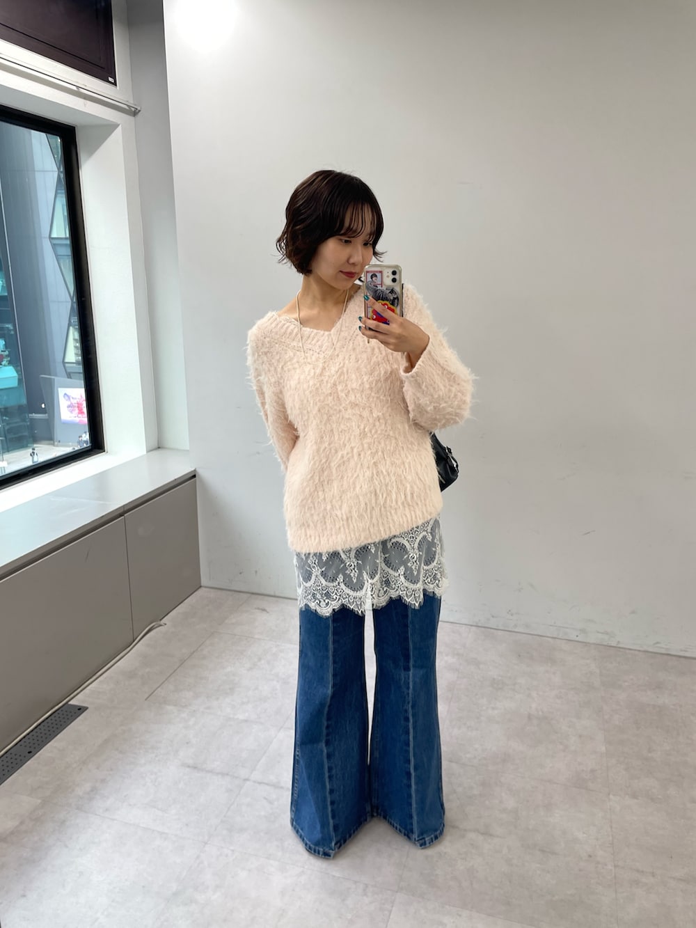 ピンク系のニット/セーター、ブラック系のトートバッグ、ブルー系のデニムパンツを着用したレディースの秋コーディネートの3枚目の写真