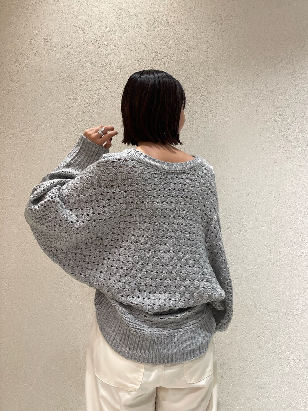 グレー系のニット/セーター、グレー系のスラックス、ブラック系のその他パンツを着用したレディースの秋コーディネートの4枚目の写真