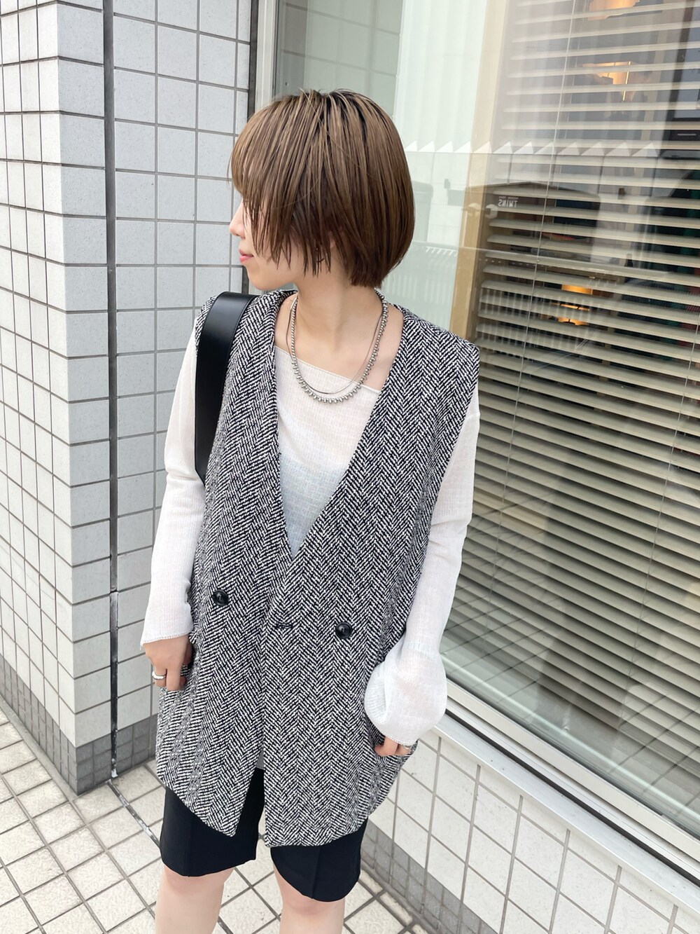 ブラック系のベスト、ホワイト系のニット/セーター、ブラック系のその他パンツを着用したレディースの秋コーディネートの2枚目の写真