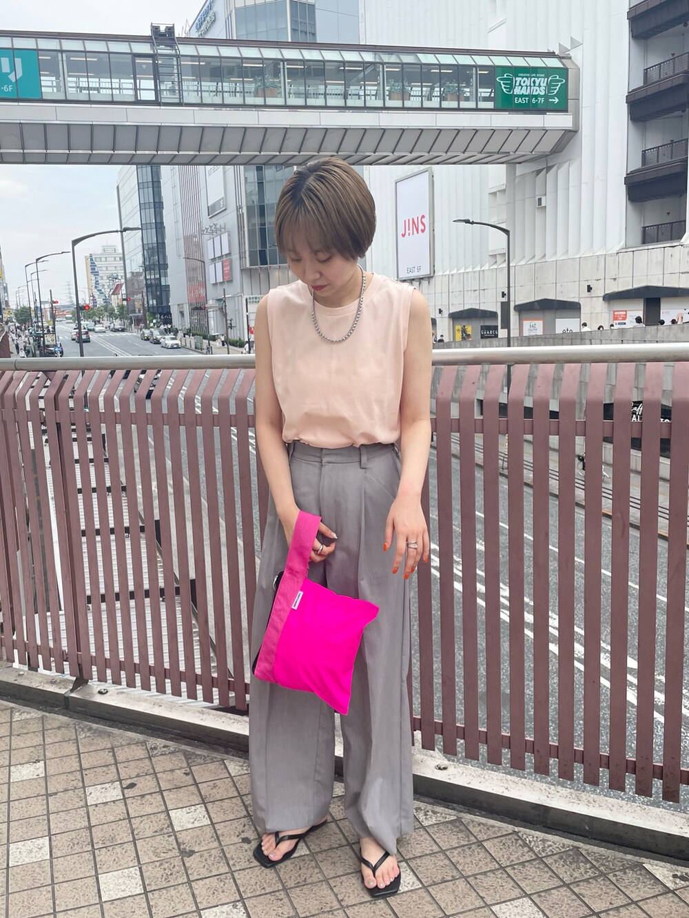 ブルー系のハンドバッグ、グレー系のスラックスを着用したレディースの夏コーディネートの3枚目の写真