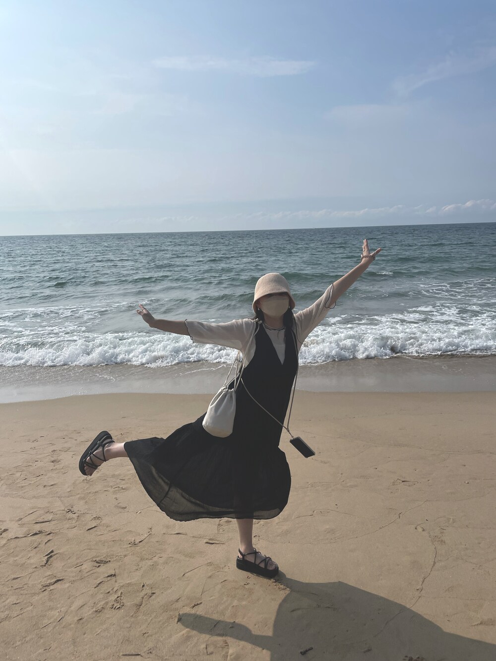 ブラック系のワンピース、ブラック系のサンダル、ベージュ系のハンドバッグを着用したレディースの秋コーディネートの3枚目の写真