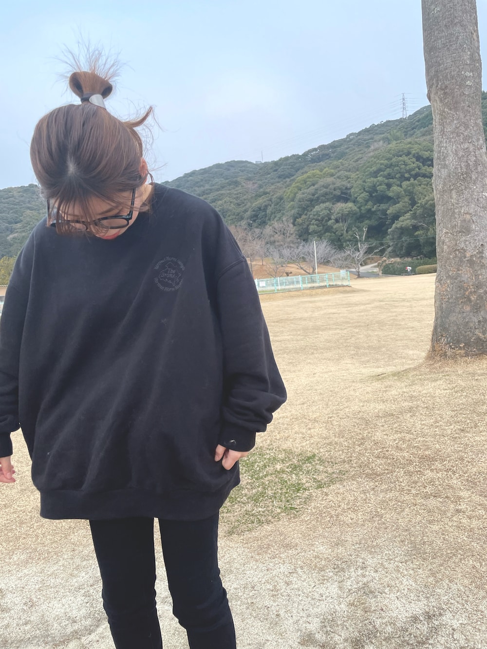 ブラック系のデニムパンツ、ホワイト系のスニーカー、ベージュ系のマフラーを着用したレディースの冬コーディネートの2枚目の写真