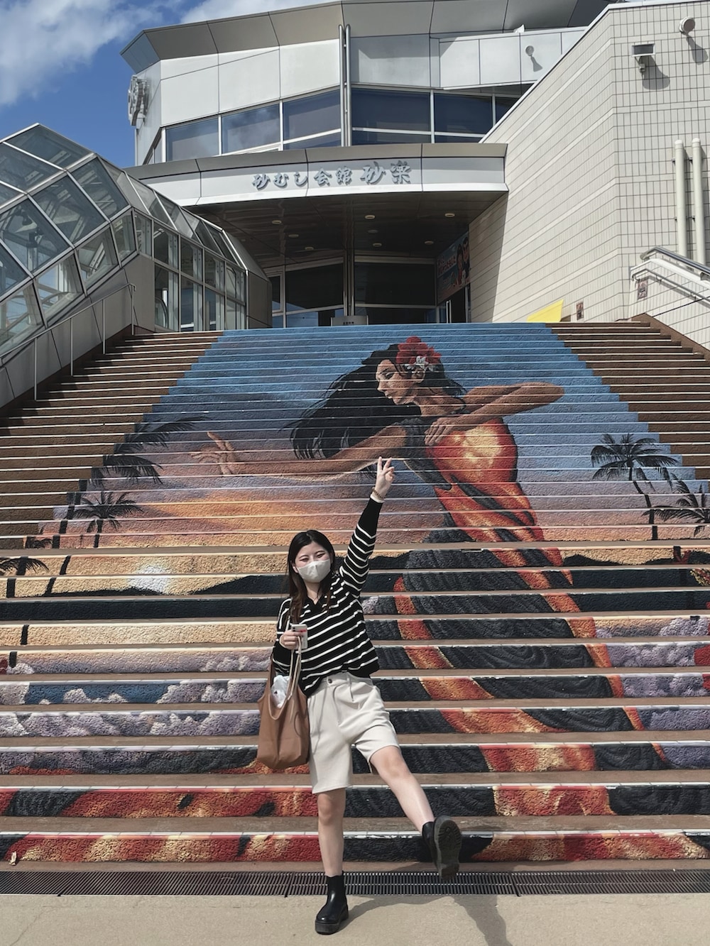 ブラウン系のトートバッグ、ブラウン系のテーラードジャケット、ブラック系のワンピースを着用したレディースの秋コーディネートの2枚目の写真