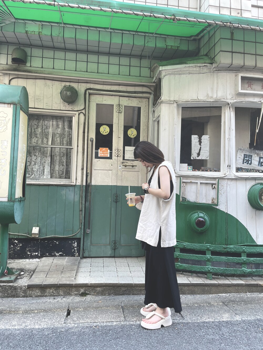 ホワイト系のベスト、ブラック系のワンピース、ホワイト系のサンダルを着用したレディースの秋コーディネートの2枚目の写真