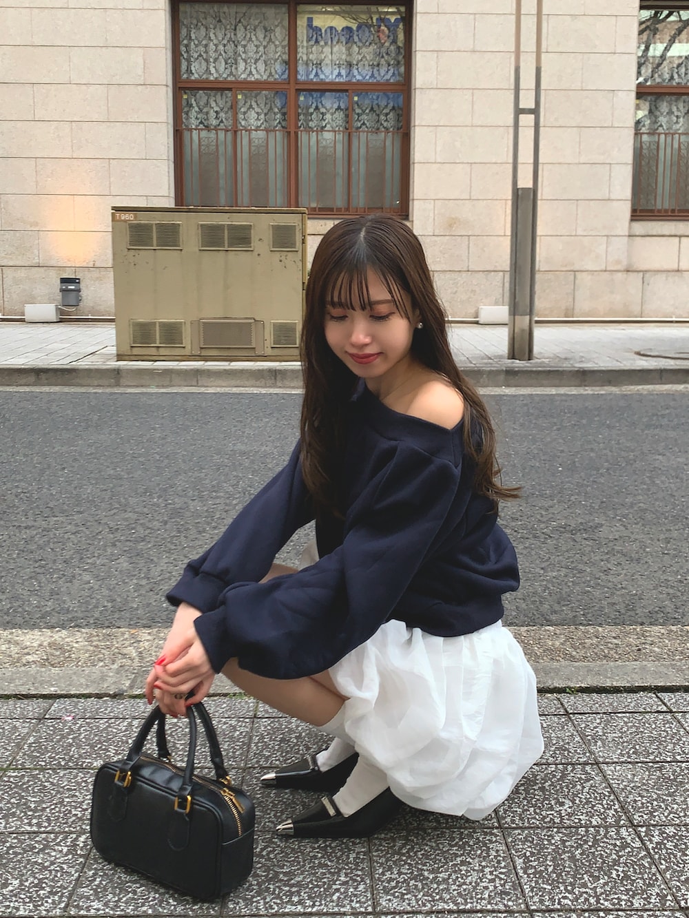 ブルー系のスウェット、ブラック系のパンプス、ブラック系のハンドバッグを着用したレディースの春コーディネートの2枚目の写真