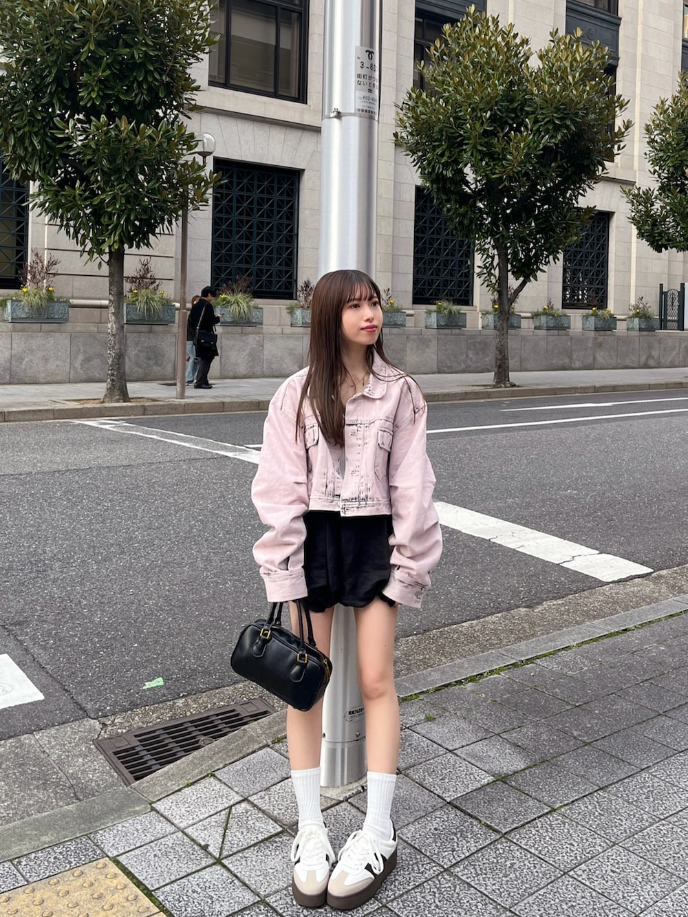 ピンク系のデニムジャケット、ホワイト系のスニーカー、ブラック系のハンドバッグを着用したレディースの春コーディネートの3枚目の写真