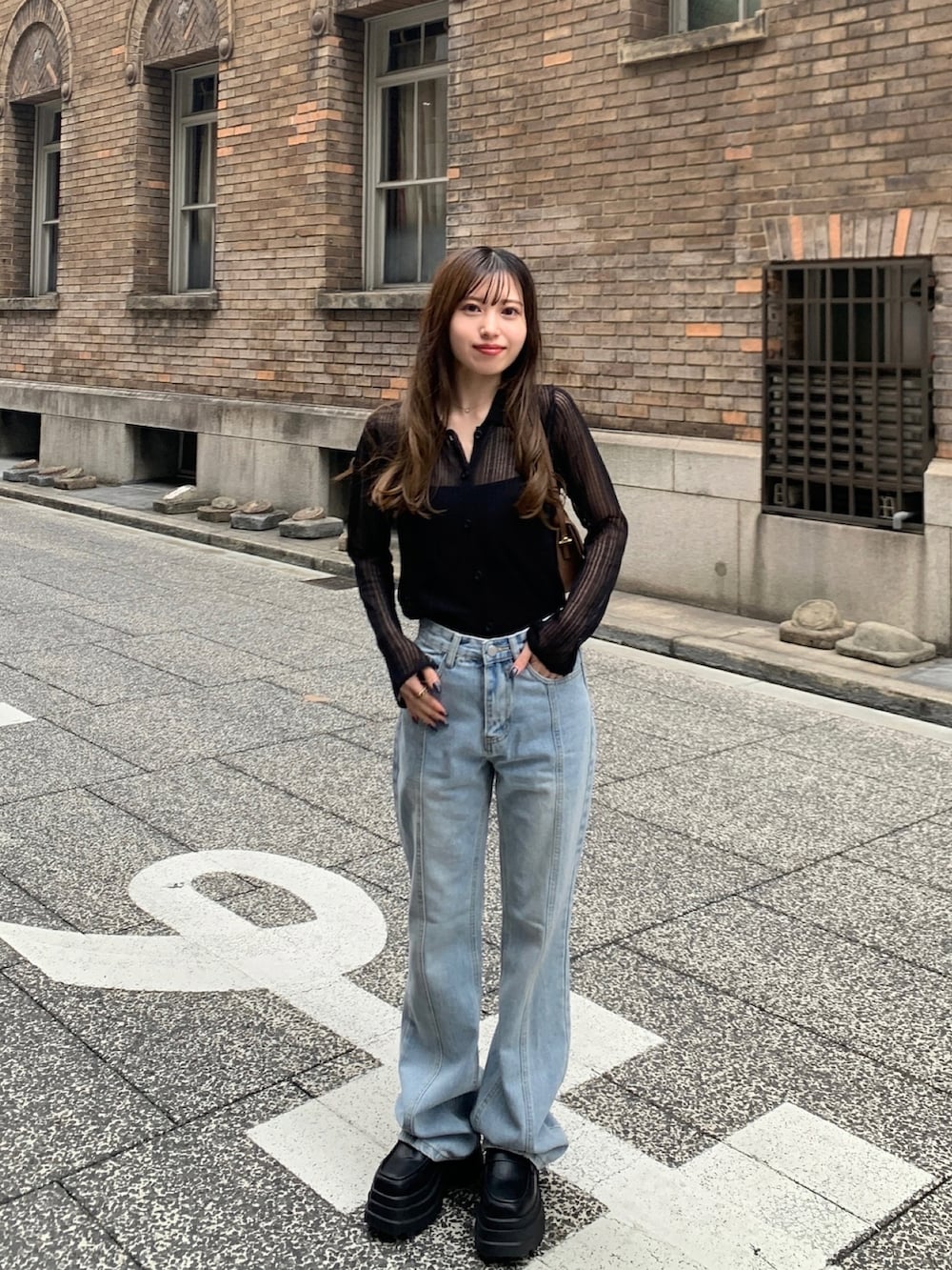 ブラック系のニット/セーター、ホワイト系のローファー、ブルー系のデニムパンツを着用したレディースの春コーディネートの3枚目の写真