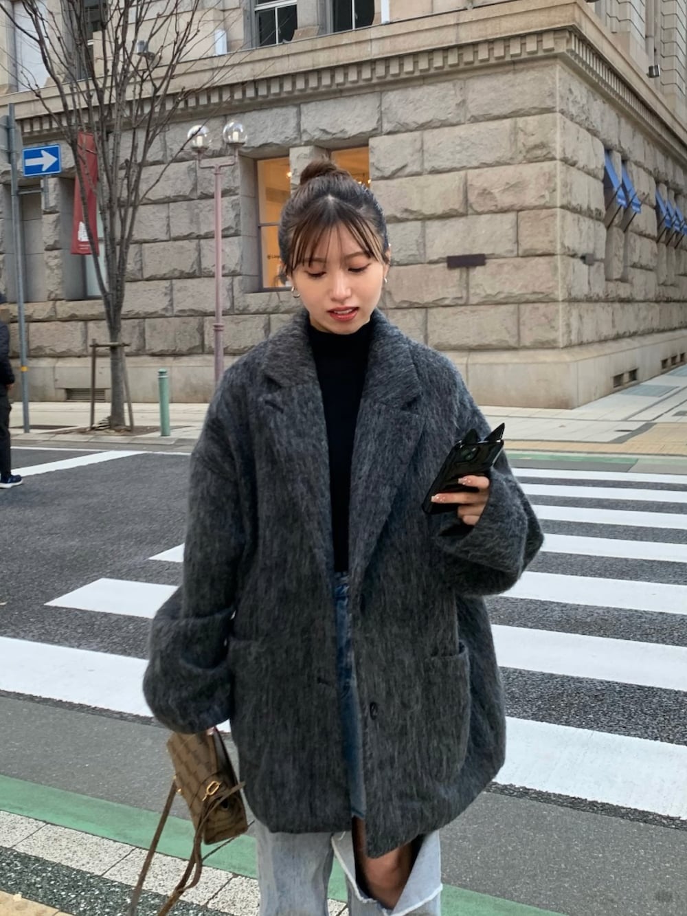 ブルー系のデニムパンツ、ブラック系のローファー、ブラック系のチェスターコートを着用したレディースの冬コーディネートの4枚目の写真