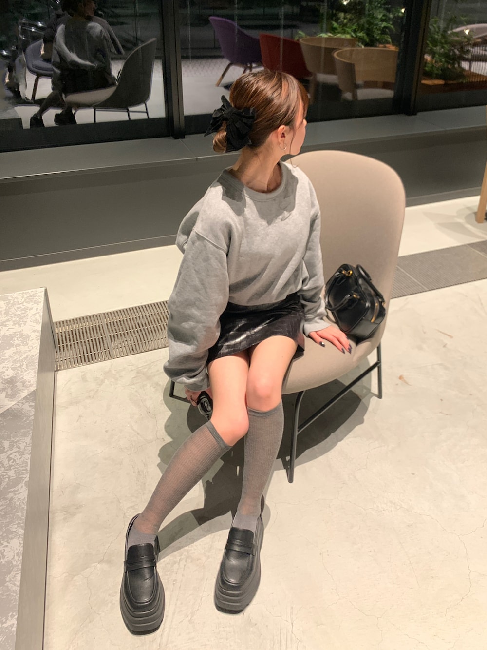 グレー系のスウェット、ブラック系のスカート、ホワイト系のローファーを着用したレディースの春コーディネートの2枚目の写真