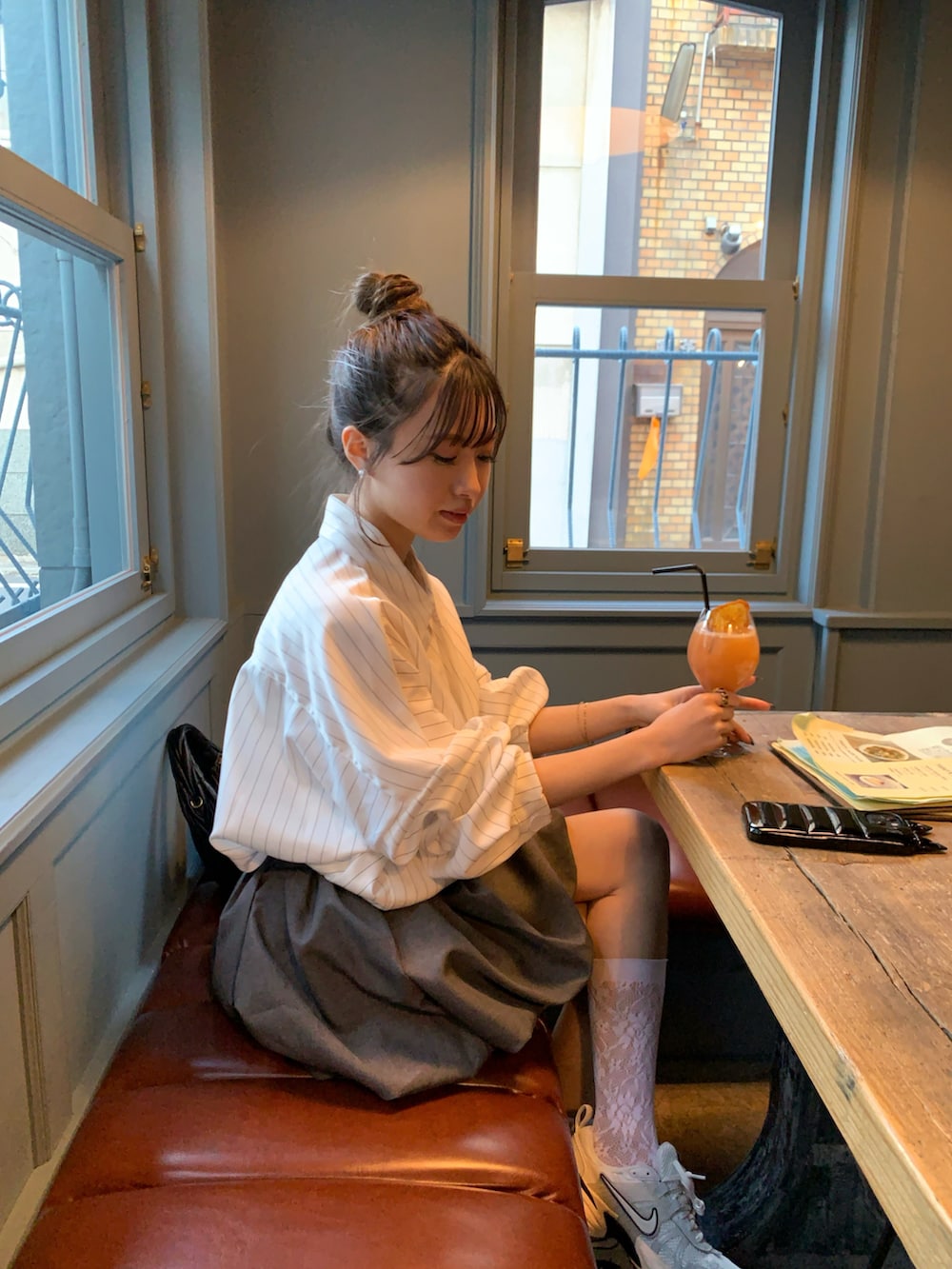 グレー系のスニーカー、ブラック系のハンドバッグ、グレー系のスカートを着用したレディースの春コーディネートの2枚目の写真