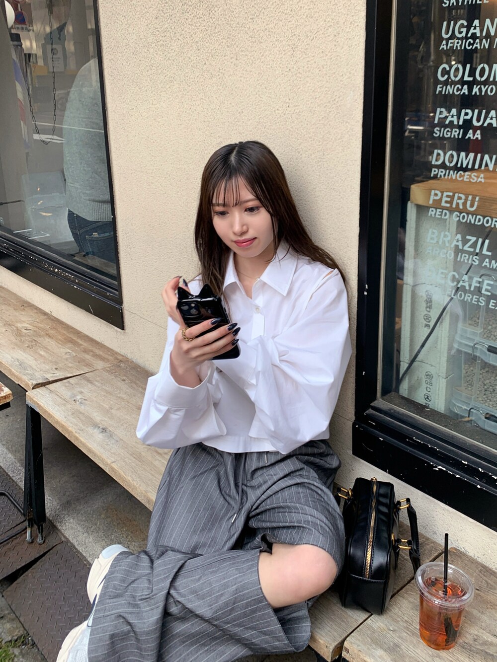 グレー系のスラックス、グレー系のスニーカー、ブラック系のハンドバッグを着用したレディースの春コーディネートの2枚目の写真