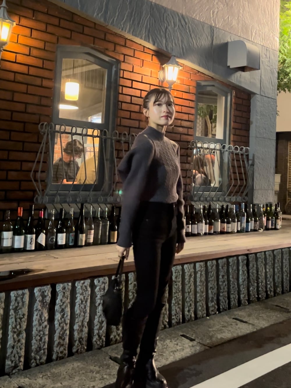 グレー系のニット/セーター、ブラック系のデニムパンツ、ブラック系のブーツを着用したレディースの秋コーディネートの3枚目の写真