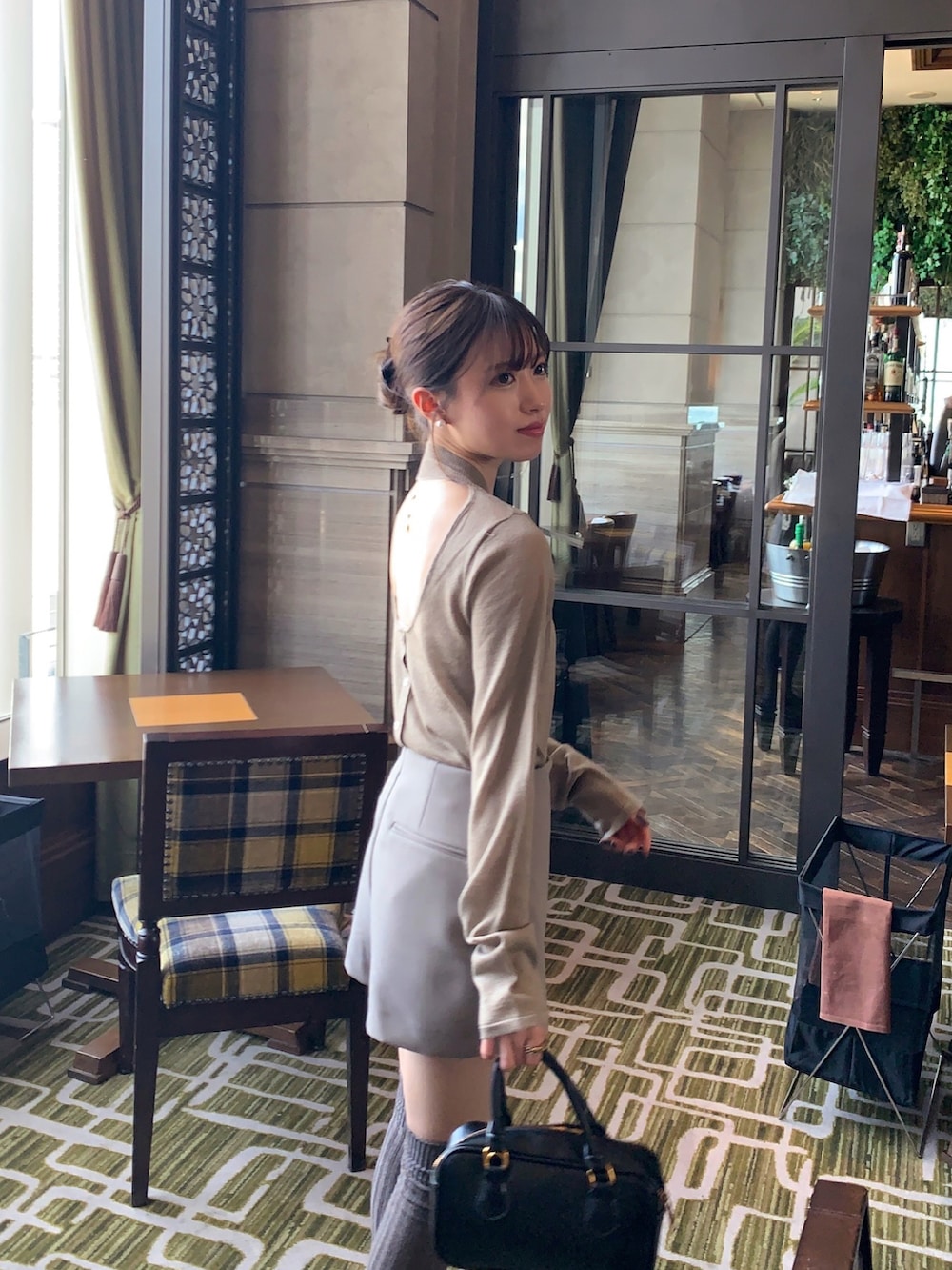 ブラウン系のニット/セーター、ベージュ系のパンツ、ブラック系のハンドバッグを着用したレディースの春コーディネートの2枚目の写真