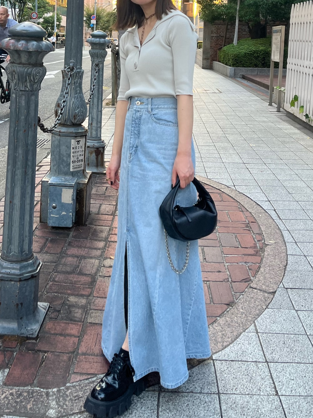 グレー系のニット/セーター、ブラック系のハンドバッグ、ブラック系のブーツを着用したレディースの秋コーディネートの2枚目の写真