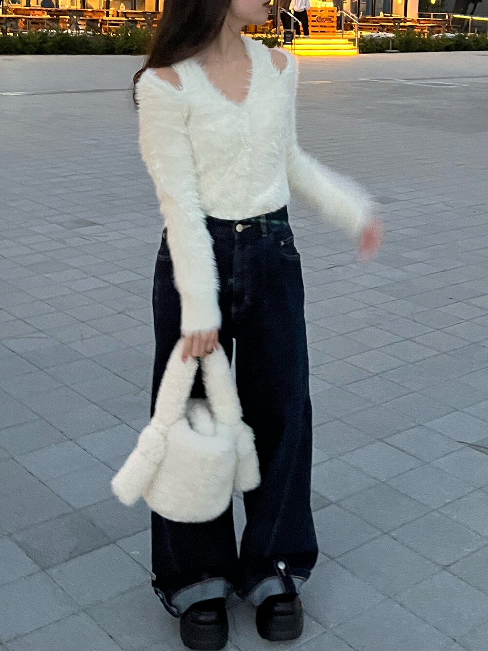 ブルー系のデニムパンツ、ホワイト系のハンドバッグ、ホワイト系のニット/セーターを着用したレディースの秋コーディネートの2枚目の写真