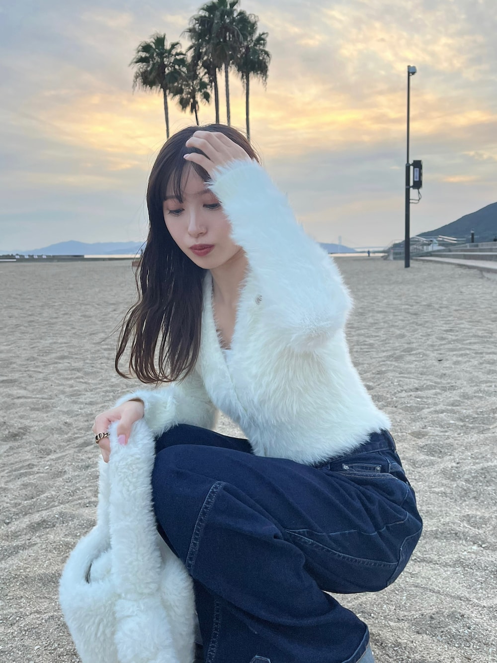 ブルー系のデニムパンツ、ホワイト系のハンドバッグ、ホワイト系のニット/セーターを着用したレディースの秋コーディネートの3枚目の写真