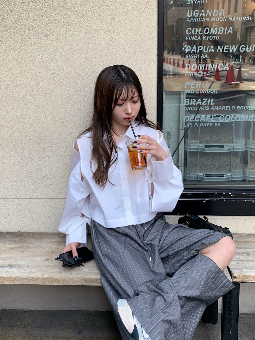 グレー系のスラックス、グレー系のスニーカー、ブラック系のハンドバッグを着用したレディースの春コーディネートの3枚目の写真