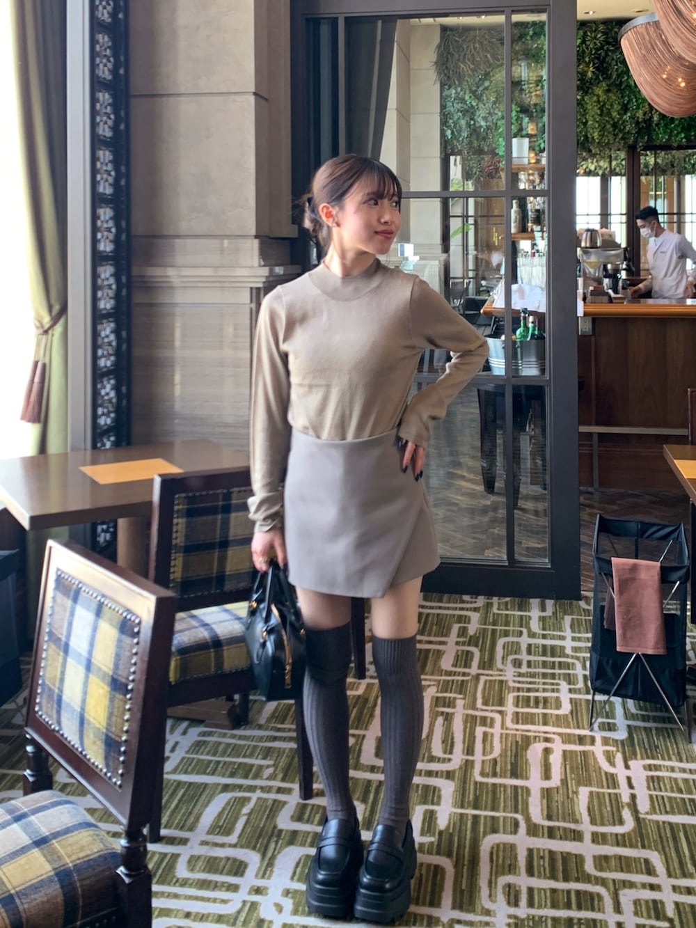 ブラウン系のニット/セーター、ベージュ系のパンツ、ブラック系のハンドバッグを着用したレディースの春コーディネートの3枚目の写真