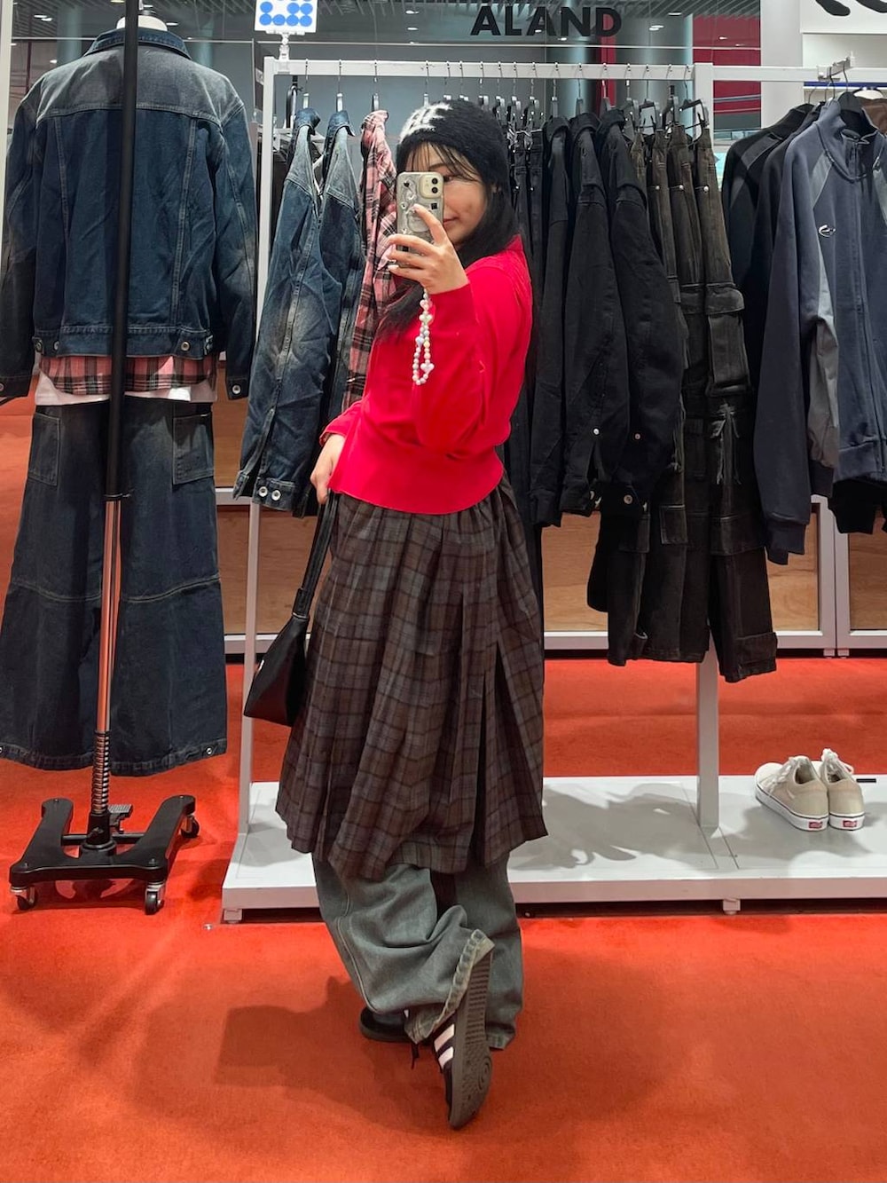 ブラック系のハンドバッグ、ブラウン系のスカート、ブルー系のデニムパンツを着用したレディースの秋コーディネートの2枚目の写真