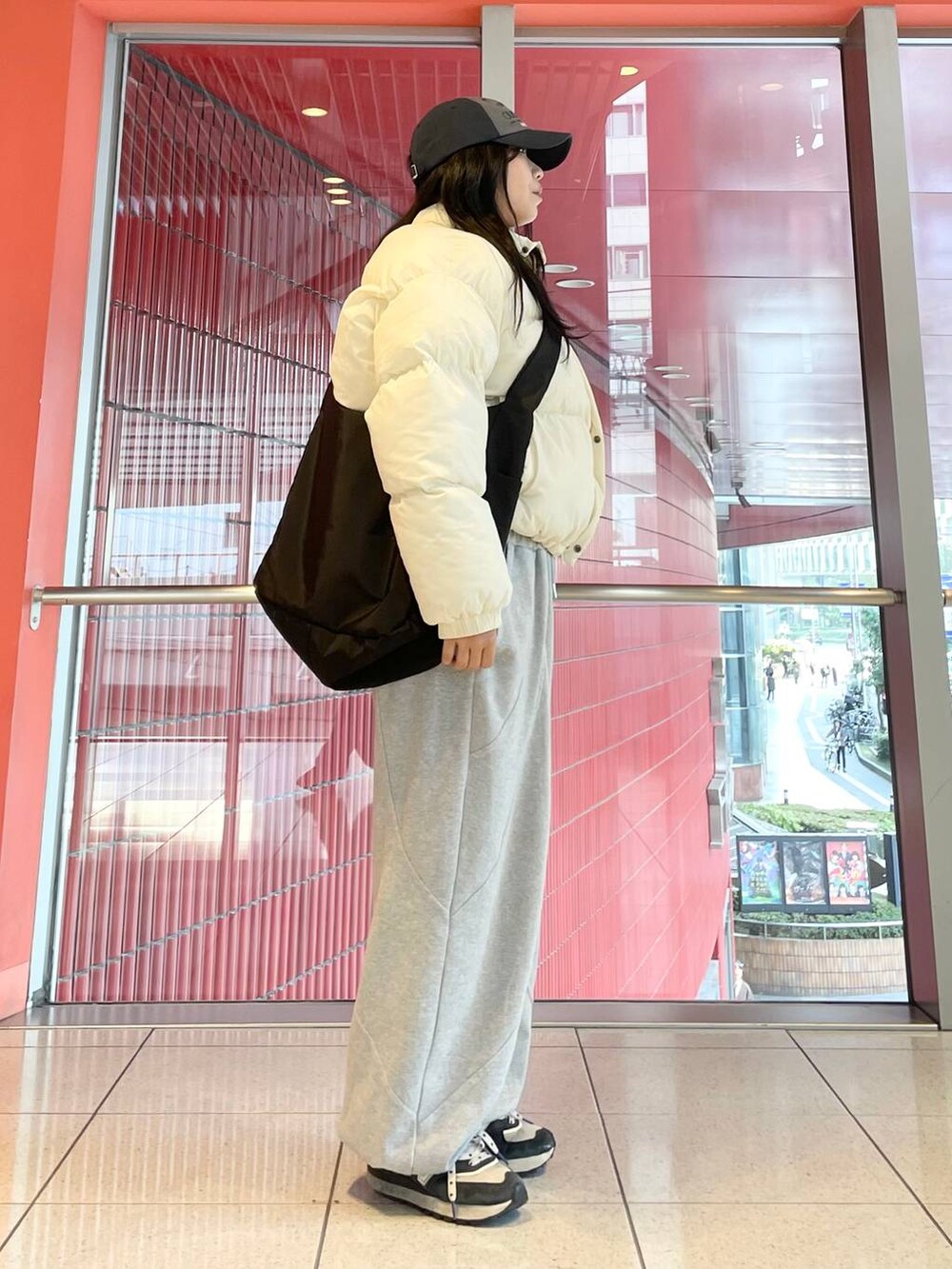 グレー系のスウェットパンツ、ブラック系のショルダーバッグ、ベージュ系のダウンジャケット/コートを着用したレディースの秋コーディネートの2枚目の写真