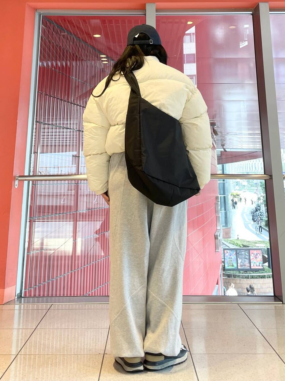 グレー系のスウェットパンツ、ブラック系のショルダーバッグ、ベージュ系のダウンジャケット/コートを着用したレディースの秋コーディネートの3枚目の写真