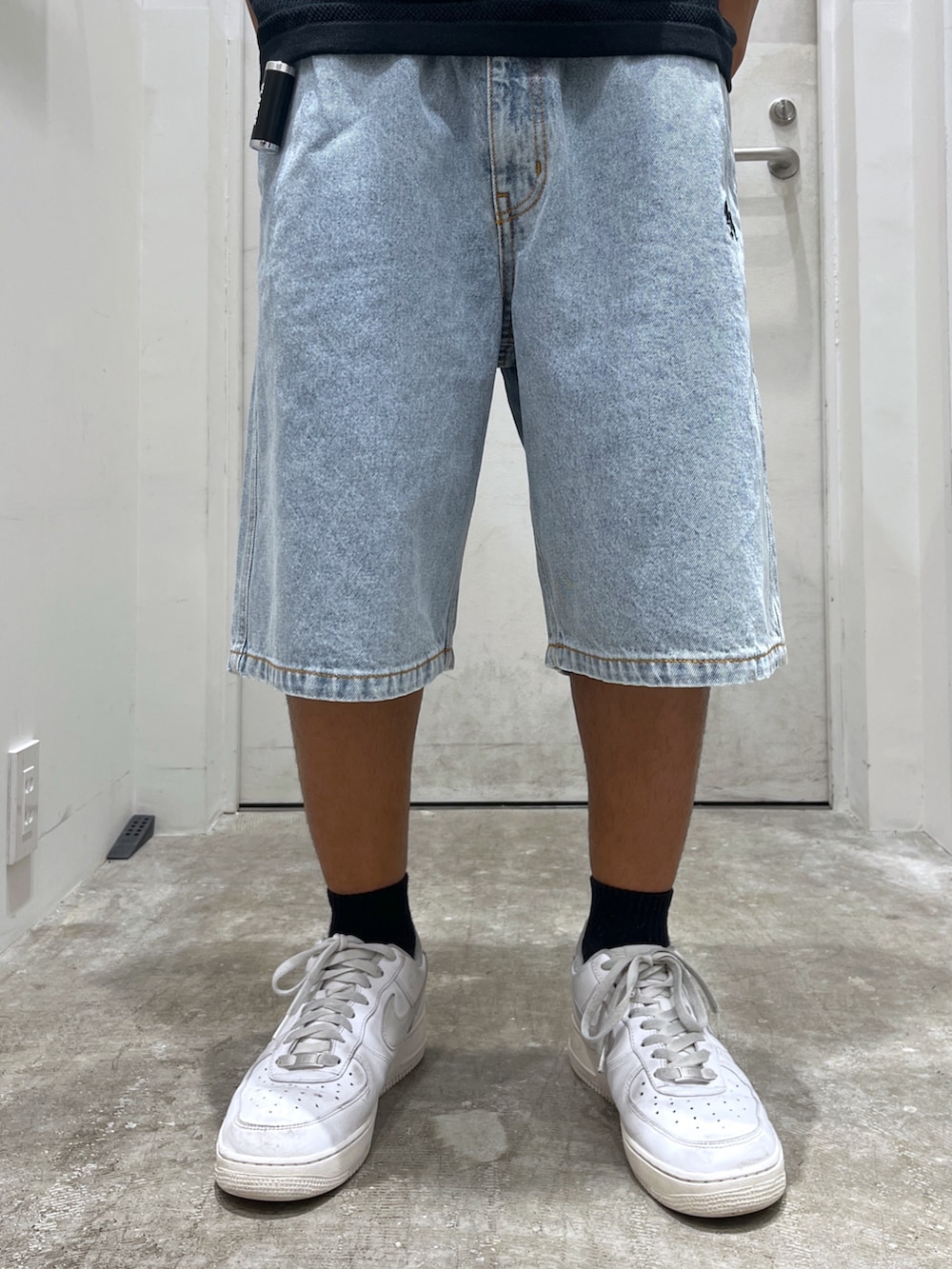 ブルー系のデニムパンツ、ブラック系のポロシャツ、ブラック系のキーホルダーを着用したメンズの夏コーディネートの4枚目の写真