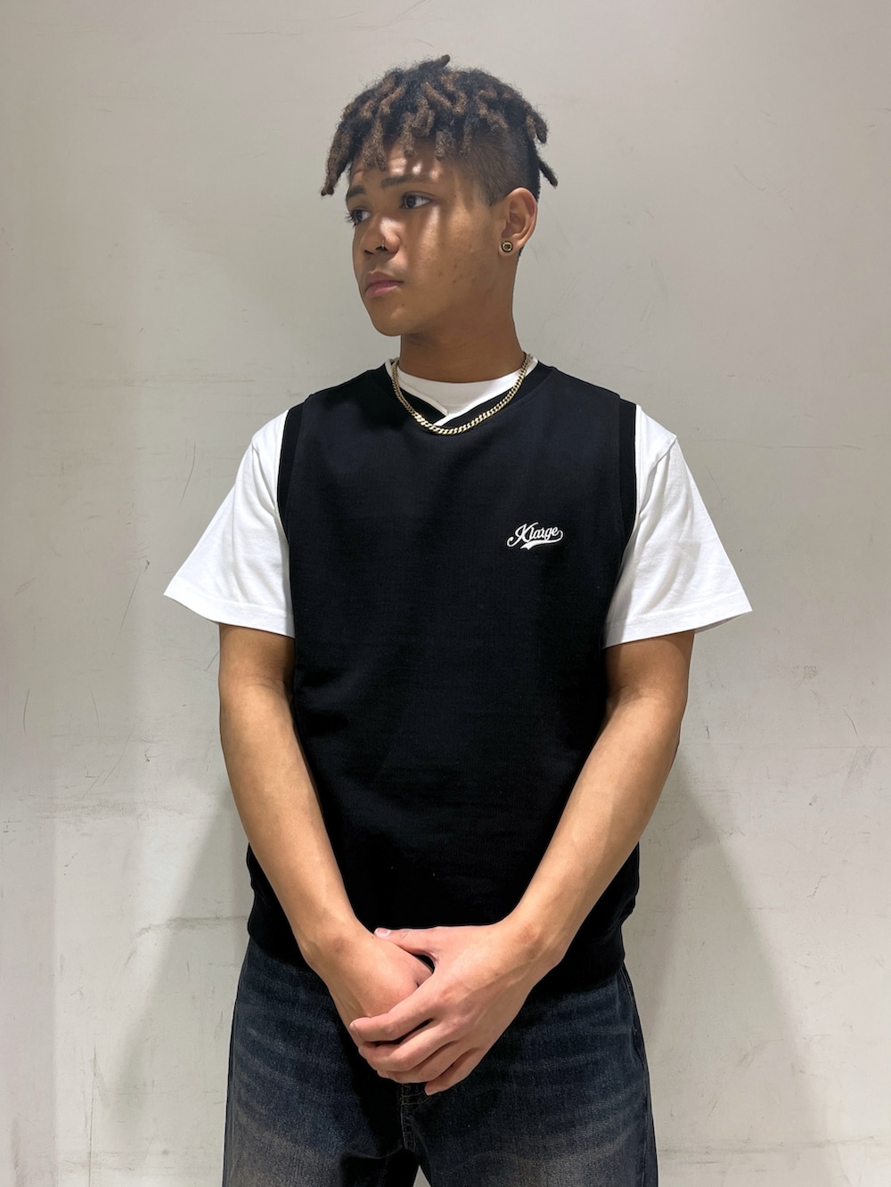 ブラック系のベスト、ブルー系のデニムパンツを着用したメンズの春コーディネートの2枚目の写真