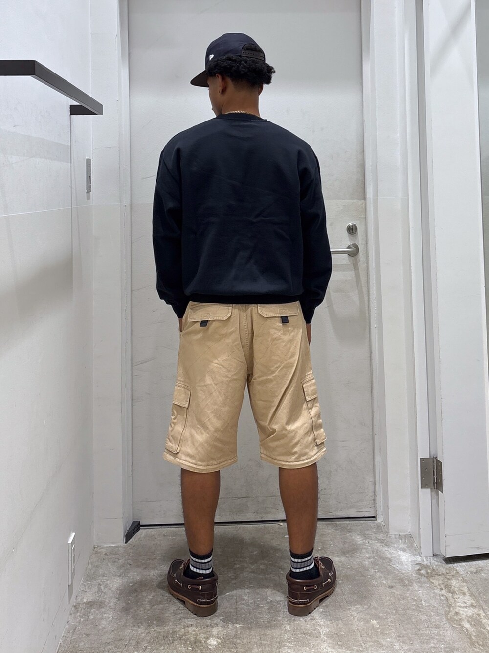 ブラック系のスウェット、ベージュ系のカーゴパンツ、ブルー系のキャップを着用したメンズの秋コーディネートの2枚目の写真