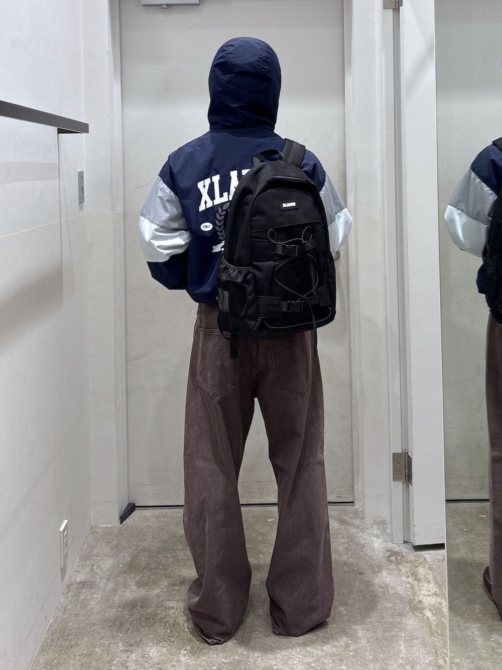 ブラウン系のデニムパンツ、ブルー系のブルゾン、ブラック系のバックパック/リュックを着用したメンズの秋コーディネートの3枚目の写真