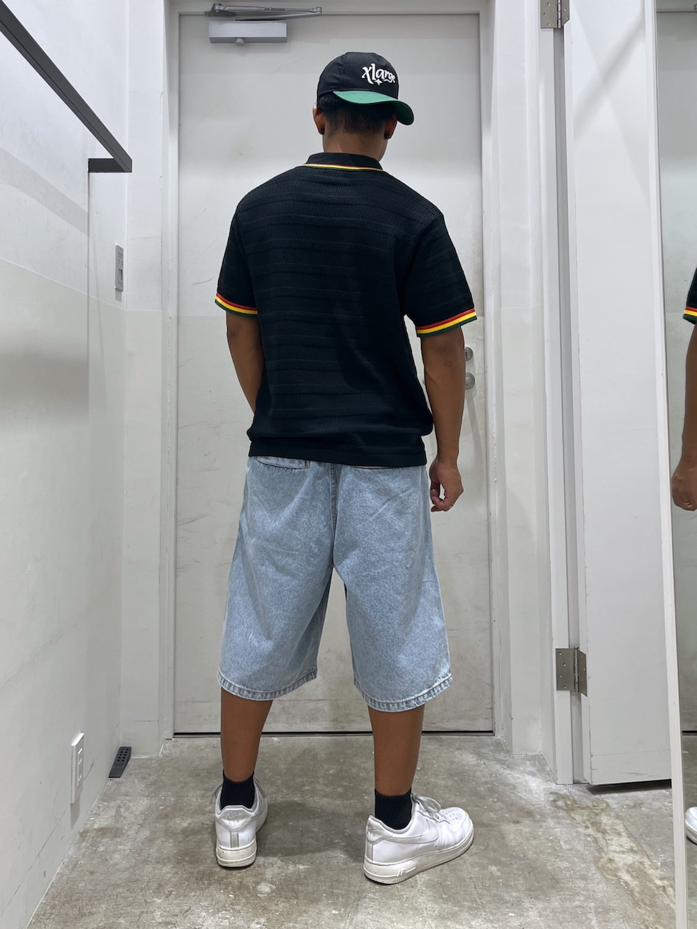 ブルー系のデニムパンツ、ブラック系のポロシャツ、ブラック系のキーホルダーを着用したメンズの夏コーディネートの2枚目の写真