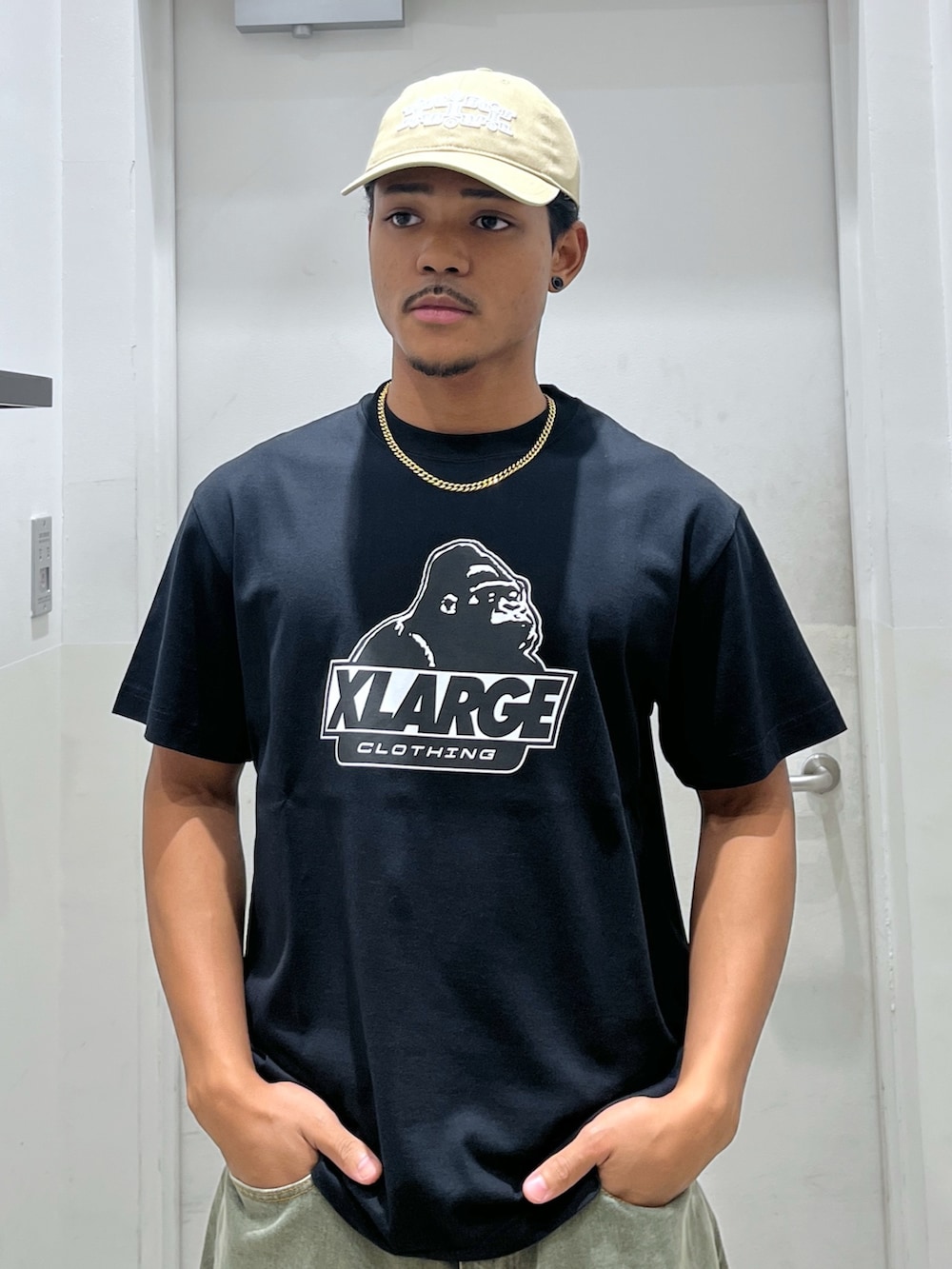 ブラック系のTシャツ/カットソー、グリーン系のデニムパンツ、ブラック系のショルダーバッグを着用したメンズの夏コーディネートの2枚目の写真