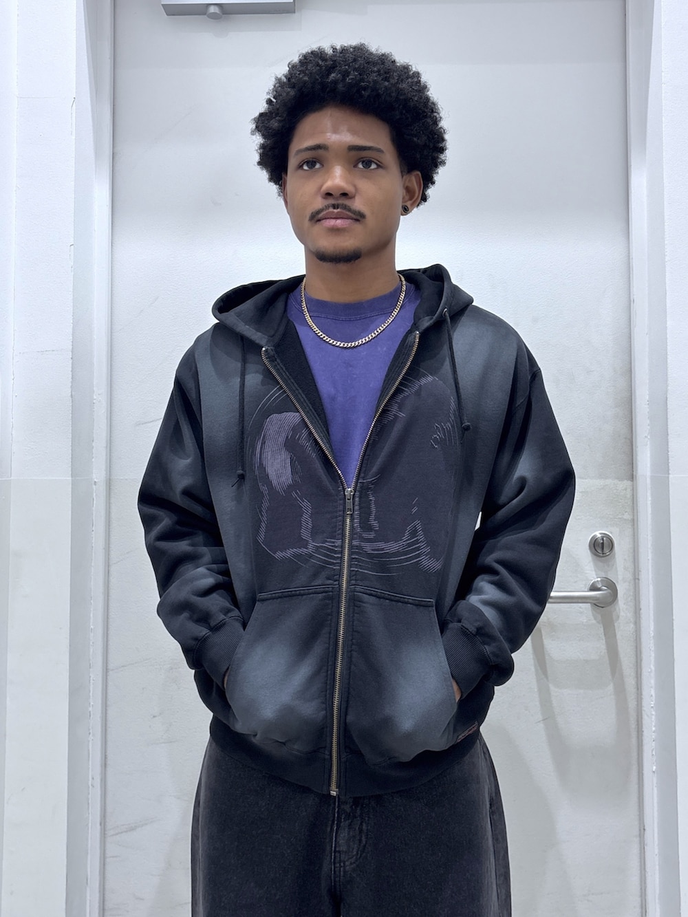 ブラック系のパーカー、パープル系のTシャツ/カットソー、ブラック系のデニムパンツを着用したメンズの秋コーディネートの3枚目の写真