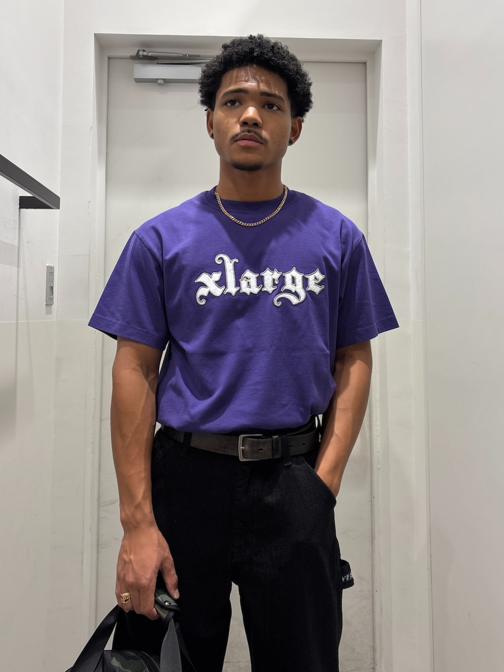 パープル系のTシャツ/カットソー、ブラック系のデニムパンツ、その他のショルダーバッグを着用したメンズの夏コーディネートの3枚目の写真