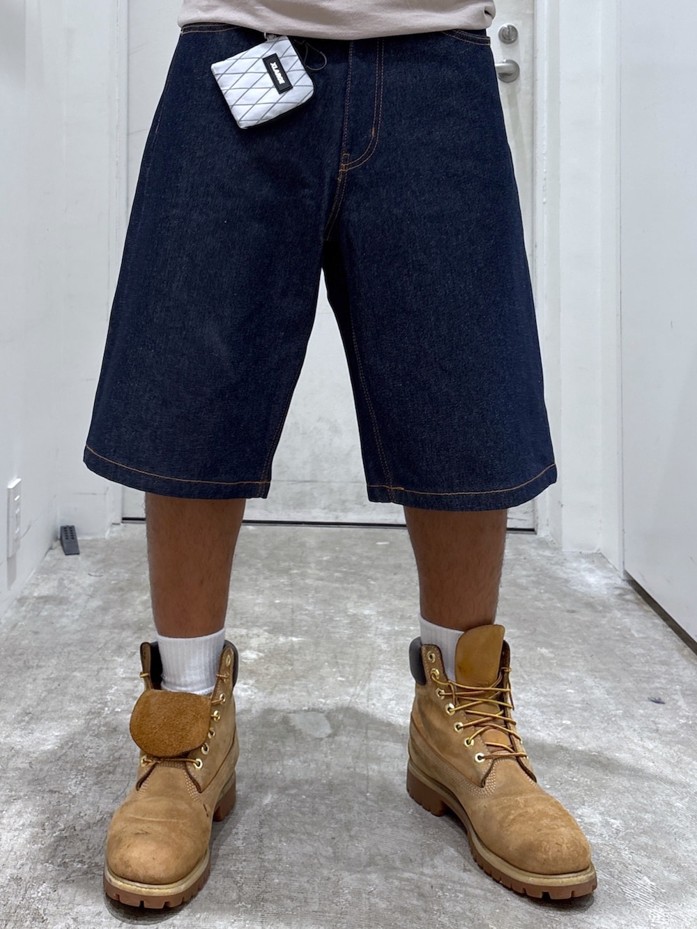 ベージュ系のTシャツ/カットソー、ブルー系のデニムパンツ、ホワイト系のコインケースを着用したメンズの夏コーディネートの4枚目の写真