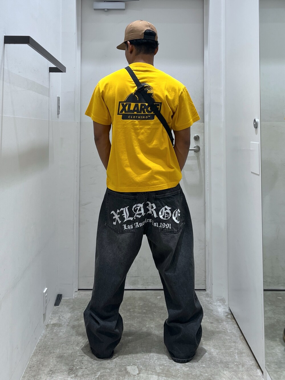 ブラック系のショルダーバッグ、ブラック系のデニムパンツ、イエロー系のTシャツ/カットソーを着用したメンズの夏コーディネートの2枚目の写真