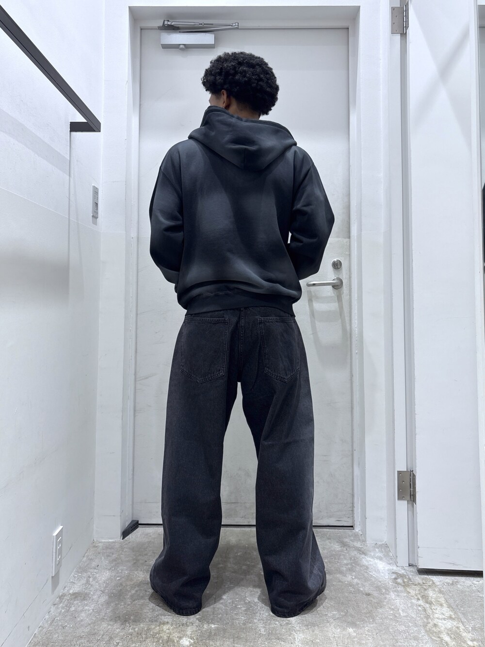 ブラック系のパーカー、パープル系のTシャツ/カットソー、ブラック系のデニムパンツを着用したメンズの秋コーディネートの2枚目の写真