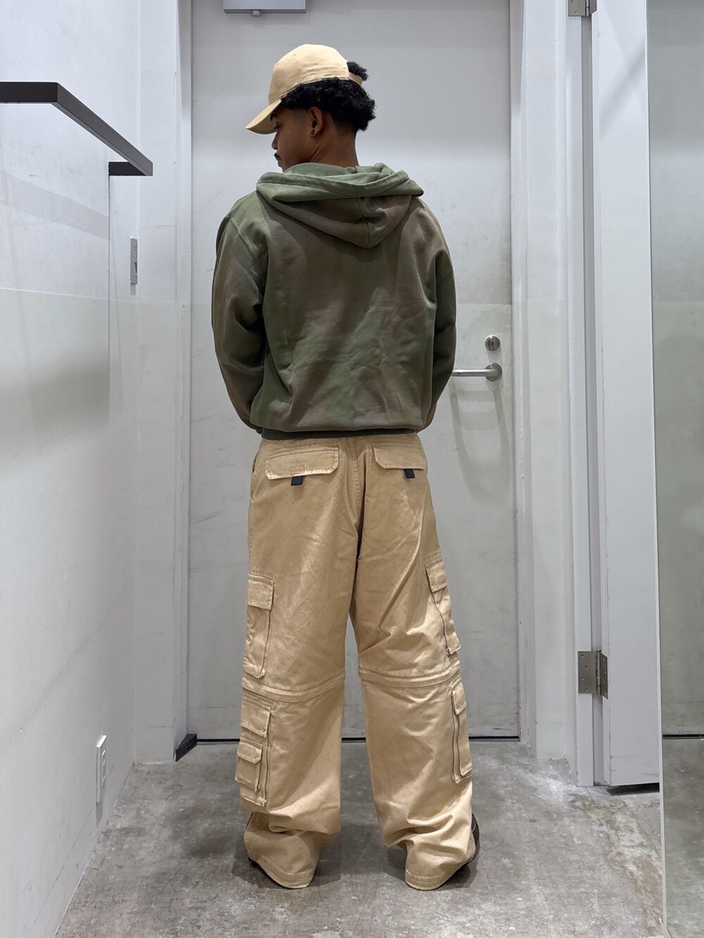 ベージュ系のカーゴパンツ、グリーン系のパーカー、ベージュ系のキャップを着用したメンズの秋コーディネートの2枚目の写真