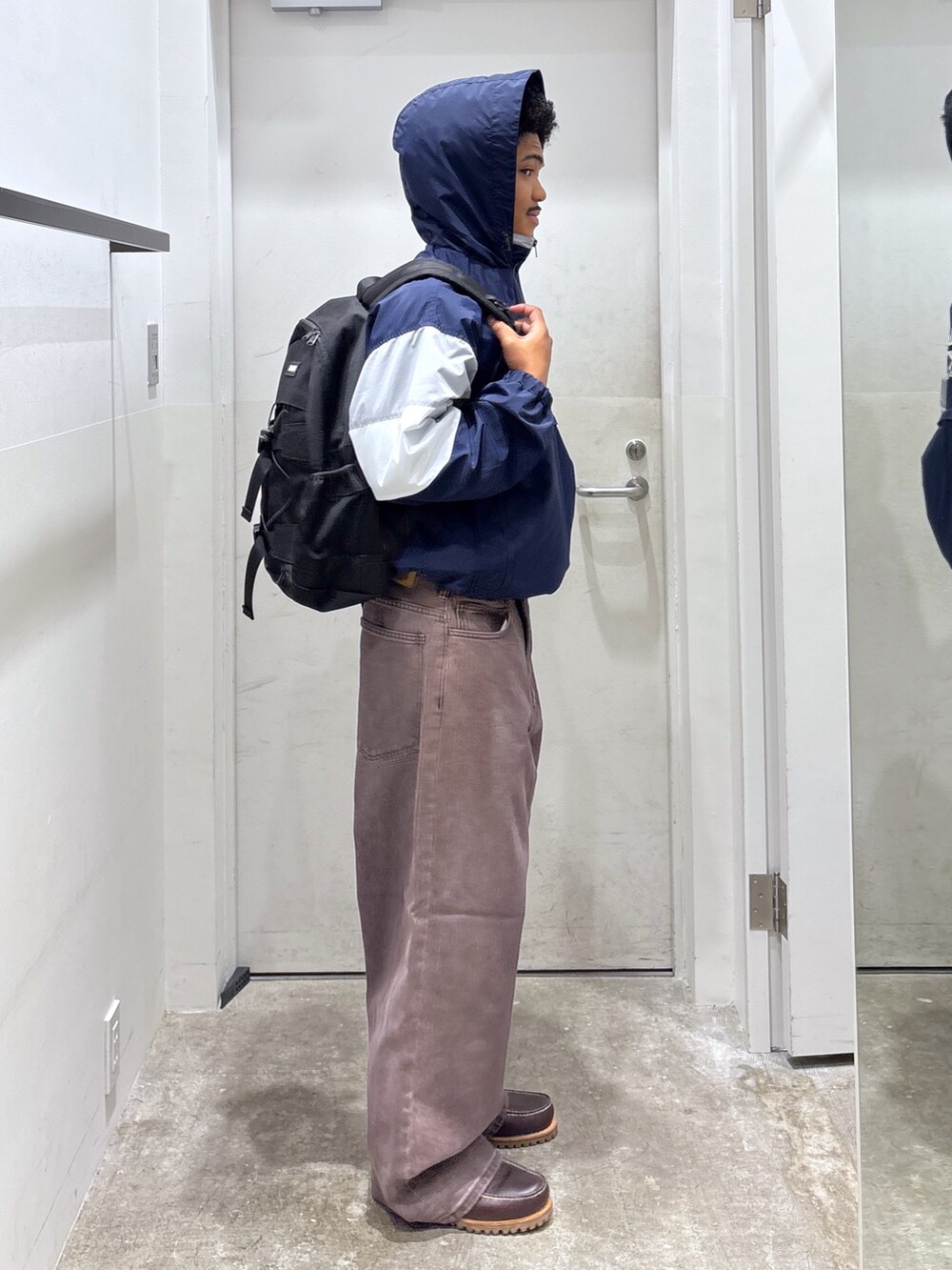 ブラウン系のデニムパンツ、ブルー系のブルゾン、ブラック系のバックパック/リュックを着用したメンズの秋コーディネートの2枚目の写真