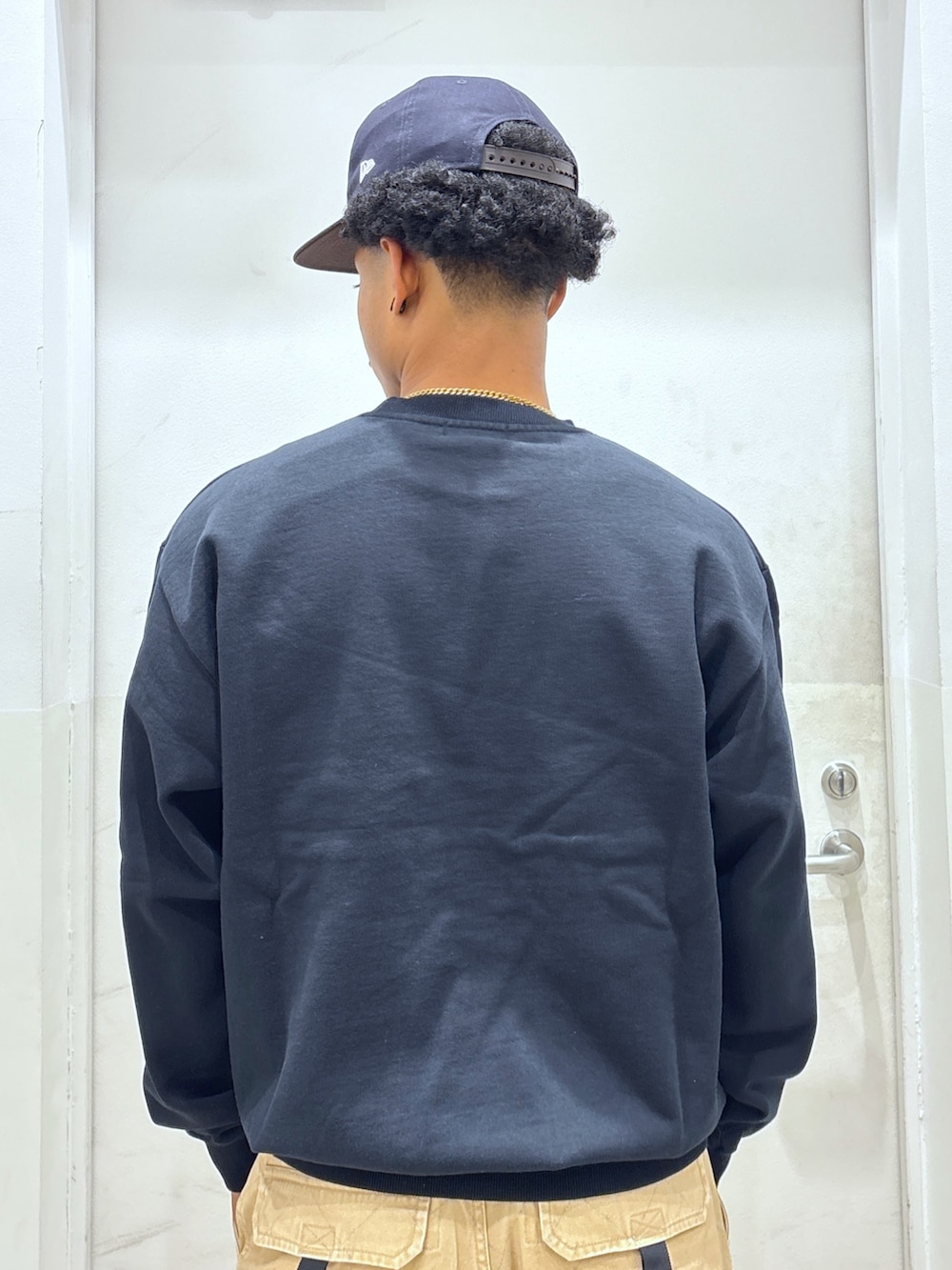 ブラック系のスウェット、ベージュ系のカーゴパンツ、ブルー系のキャップを着用したメンズの秋コーディネートの4枚目の写真