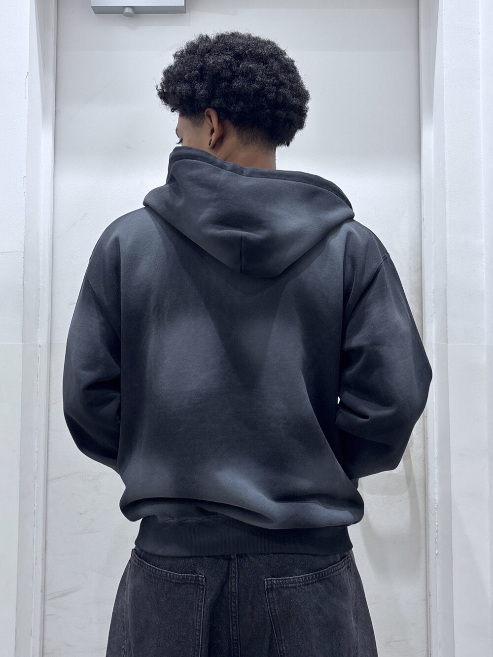 ブラック系のパーカー、パープル系のTシャツ/カットソー、ブラック系のデニムパンツを着用したメンズの秋コーディネートの4枚目の写真