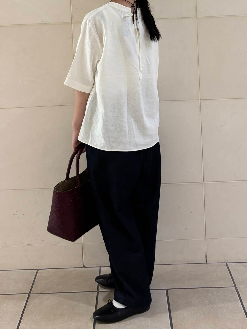 レッド系のトートバッグ、ブラック系のバレエシューズ、ホワイト系のシャツ/ブラウスを着用したレディースの夏コーディネートの4枚目の写真