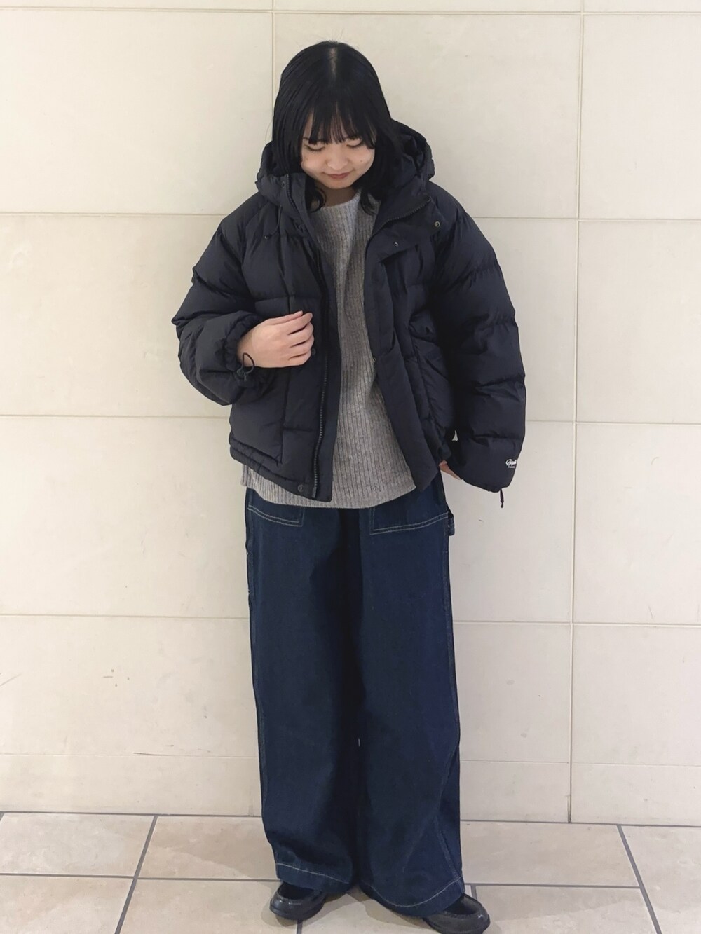 ブルー系のその他パンツ、グレー系のニット/セーター、ブラック系のダウンジャケット/コートを着用したレディースの冬コーディネートの2枚目の写真