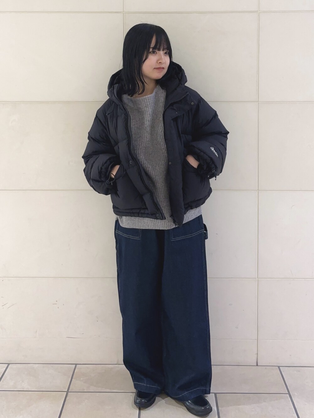 ブルー系のその他パンツ、グレー系のニット/セーター、ブラック系のダウンジャケット/コートを着用したレディースの冬コーディネートの3枚目の写真