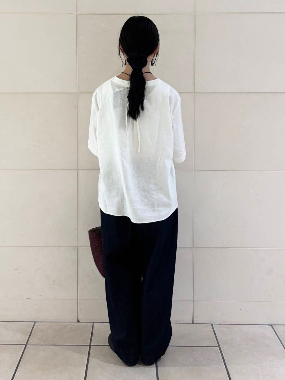 レッド系のトートバッグ、ブラック系のバレエシューズ、ホワイト系のシャツ/ブラウスを着用したレディースの夏コーディネートの3枚目の写真