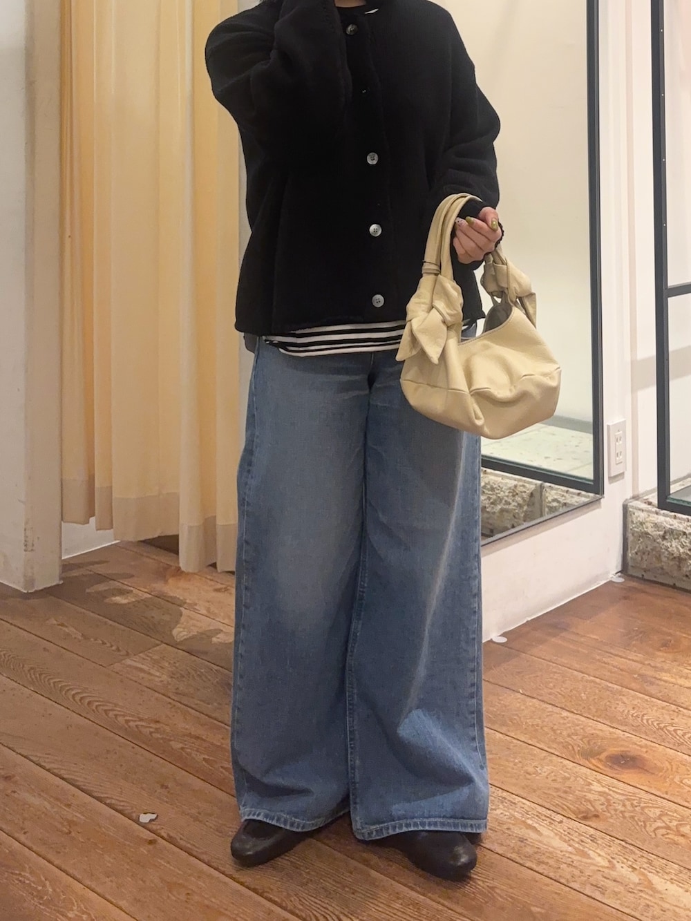 ブルー系のデニムパンツ、ブラック系のローファー、ベージュ系のハンドバッグを着用したレディースの冬コーディネートの3枚目の写真